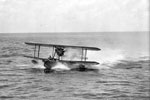 A Supermarine Walrus amphibious aircraft from HMS Mauritius lands on the sea after her patrol flight and makes her way towards the cruiser. Imperial War Museums A8910