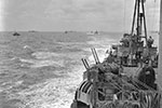 HMS Mauritius ready for action with other Allied shipping off the beachhead at Anzio, Italy in March 1944. Note the twin 4 inch guns at full elevation on the starboard side of the cruiser. She was adopted by Kingston-upon-Hull. Imperial War Museums A22535